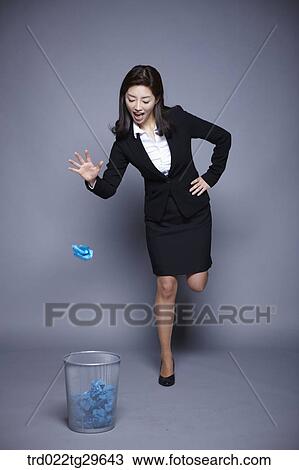 Stock Image - woman throw garbage to waste basket. Fotosearch