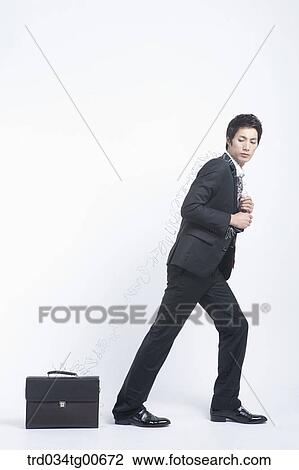 Stock Image - A man dragging the suitcase with twisted wire. Fotosearch