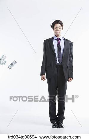 Picture - A man hard to stand and flying money. Fotosearch
