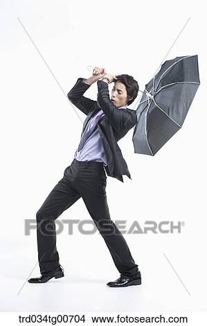 Picture - A man hit by the strong wind with an umbrella inside out. Fotosearch