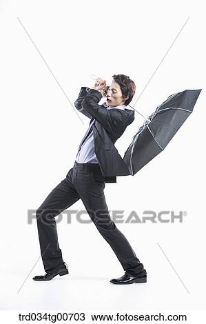 Stock Image - A man hit by the strong wind with an umbrella inside out. Fotosearch