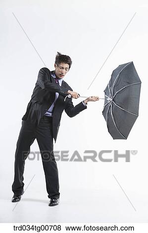 Stock Photo - A man hit by the strong wind with an umbrella inside out. Fotosearch