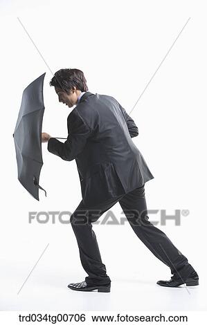 A man trying to walk forward with defending umbrella View Large Photo Image Stock Photograph - A man trying to walk forward with defending umbrella. Fotosearch