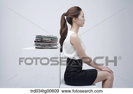A sitting woman with the pile of document behind View Large Photo Image Stock Photo - A sitting woman with the pile of document behind. Fotosearch