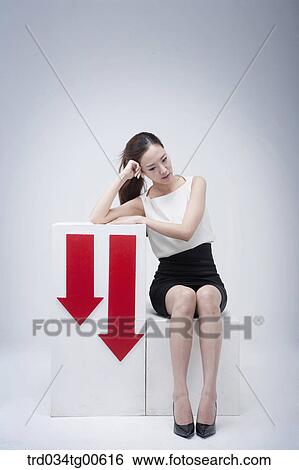 A stressful woman beside going down arrows View Large Photo Image Stock Photograph - A stressful woman beside going down arrows. Fotosearch