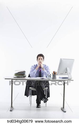 Stock Photo - A thinking man while sitting on his desk. Fotosearch