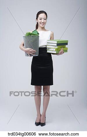 Stock Photograph - A woman holding the grass basket and green books. Fotosearch