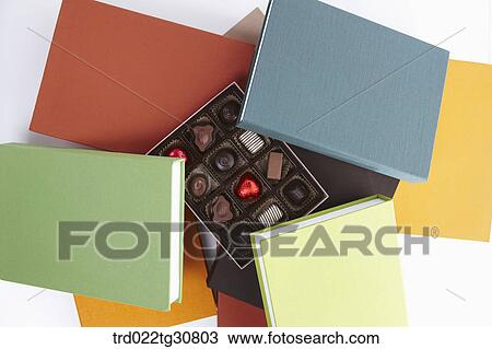 Stock Image - A box of chocolate in the middle of books. Fotosearch