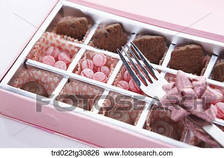 Stock Photograph - A box of sweets and a folk with ribbon. Fotosearch