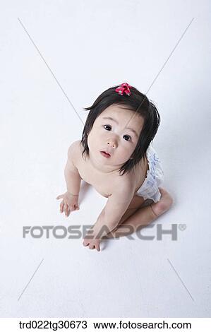 Stock Image - Baby girl in nappy with red ribbon. Fotosearch