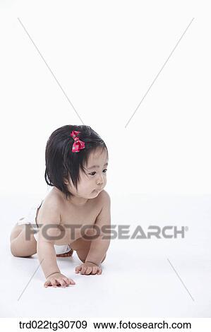 Stock Photo - Baby girl in nappy with red ribbon crawling. Fotosearch
