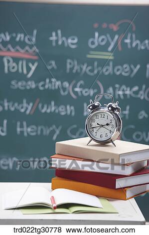 Stock Photo - Books and an alarm clock with blackboard. Fotosearch