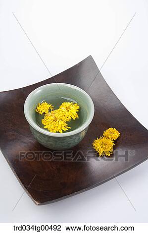 Stock Image - Cup of dandelion tea and its flowers. Fotosearch