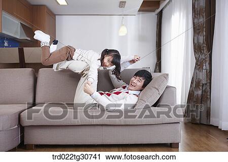 Stock Image - Father and daughter playing on the sofa. Fotosearch