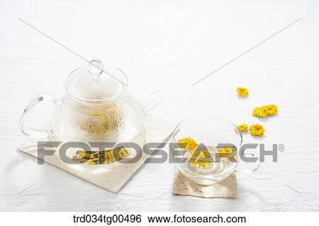 Stock Photograph - Glass tea pot and a cup of dandelion tea. Fotosearch