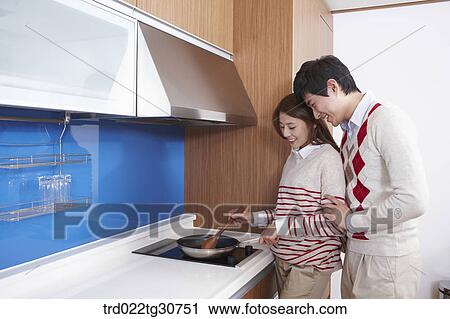 Stock Image - Happy couple cooking together in the kitchen. Fotosearch