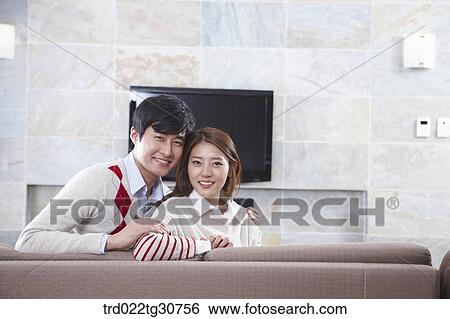 Stock Photograph - Happy couple on the sofa and a televison. Fotosearch