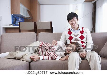 Stock Photo - Happy couple sitting on a sofa with a cup. Fotosearch