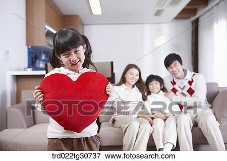 Happy family and a girl holding a red heart cushion View Large Photo Image Stock Photo - Happy family and a girl holding a red heart cushion. Fotosearch