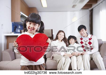 Happy family and a girl holding a red heart cushion View Large Photo Image Stock Photograph - Happy family and a girl holding a red heart cushion. Fotosearch