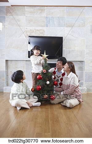 Happy family decorating a christmas tree View Large Photo Image Stock Image - Happy family decorating a christmas tree. Fotosearch