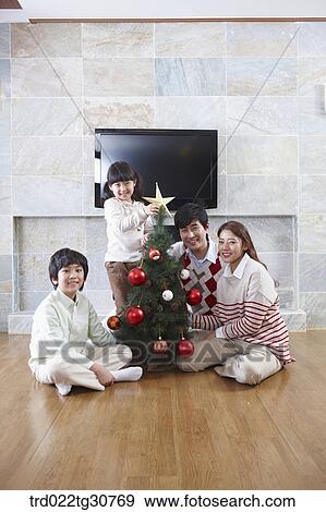 Happy family decorating a christmas tree View Large Photo Image Stock Photo - Happy family decorating a christmas tree. Fotosearch