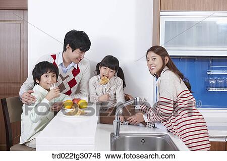 Stock Photo - Happy family on the kitchen top eating. Fotosearch