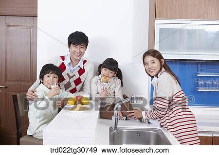 Stock Photo - Happy family on the kitchen top eating. Fotosearch