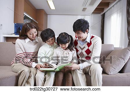 Stock Photo - Happy family reading a book on the sofa. Fotosearch