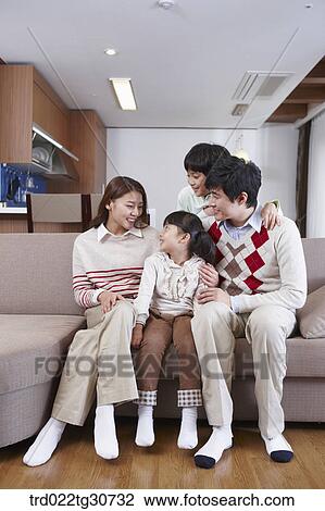 Stock Image - Happy family talking on the sofa. Fotosearch