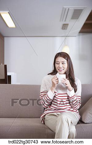 Happy woman with a cup on the sofa View Large Photo Image Stock Image - Happy woman with a cup on the sofa. Fotosearch