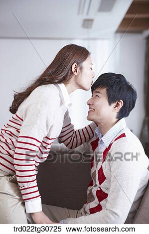 Stock Photography - Woman kissing man's forehead on the sofa. Fotosearch