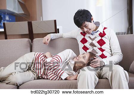 Stock Image - Woman resting on man's lap on the sofa. Fotosearch