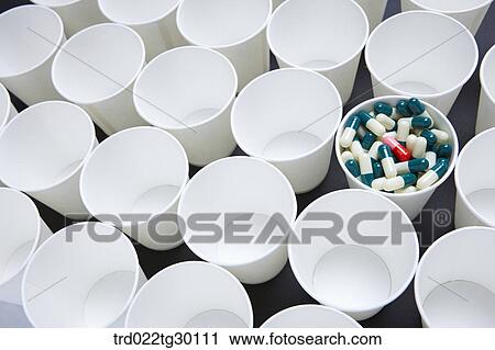 Stock Image - A cup full of tablets with other paper cups empty. Fotosearch