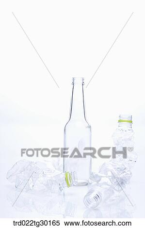 Stock Photography - A glass bottle and other crumpled plastic bottles. Fotosearch