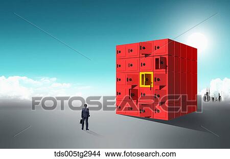 Picture - A man standing at big locker box. Fotosearch