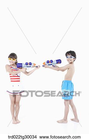 Picture - boy and girl are holding water guns on each other. Fotosearch