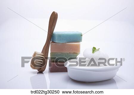 Stock Image - Colorful pile of soaps, bath brush and soap with foam . Fotosearch