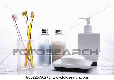 Stock Photography - Colorful tooth brushes in cup, Bottles of bath salt, shampoo and soap . Fotosearch