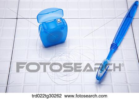 Stock Image - Dental floss and a blue tooth brush . Fotosearch