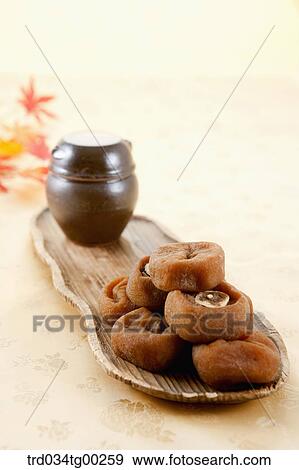 Stock Photo - Dried persimmons and small jar on wooden dish . Fotosearch