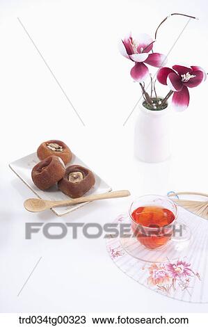 Stock Image - Dries persimmons, a cup of tea, a fan, and flowers. Fotosearch