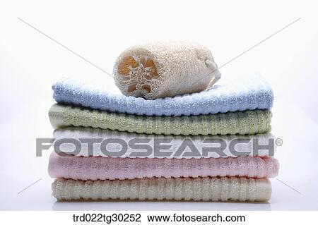 Stock Image - Folded colorful towels and bath ball on them . Fotosearch