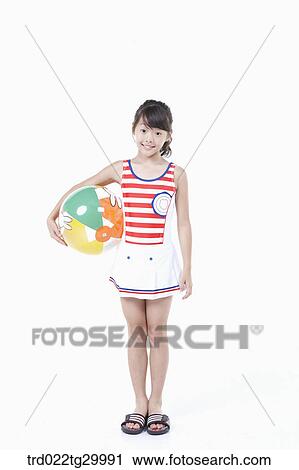 Stock Image - girl is standing with holding beach ball in her arm. Fotosearch