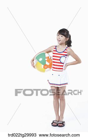 Stock Image - girl is standing with holding beach ball in her arm. Fotosearch