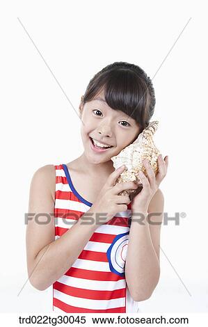 girl put the turban shell to her ear View Large Photo Image Stock Photography - girl put the turban shell to her ear. Fotosearch