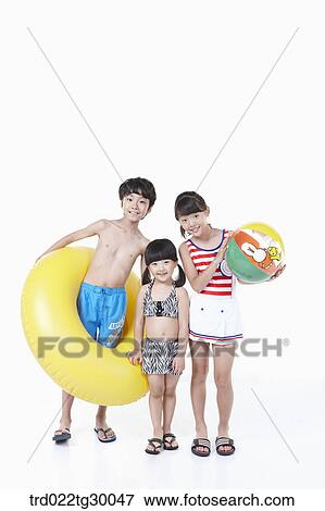Stock Photo - girls and boy are in swimsuit with tube and beach ball. Fotosearch