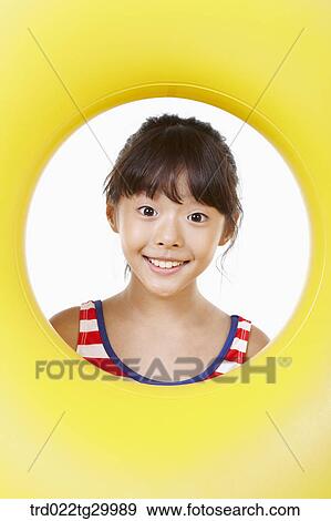 Stock Photo - girl's face was seen through the hole of tube. Fotosearch