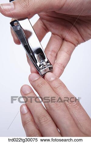Stock Photography - hands cut the nail with nail clippers. Fotosearch
