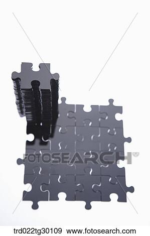 Stock Photo - Piled black puzzle on the pieces of puzzle put together. Fotosearch